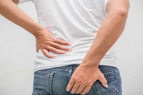 Mann hält sich den Rücken und das Gesäß. Möglicher tumor am after.