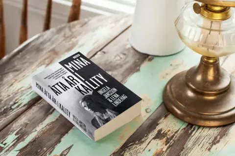 Boken "Mina åtta år i kalitet" av Ingela Jansson och Lena Lindehag ligger på ett slitet träbord.