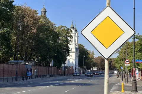Znak "koniec drogi z pierwszeństwem" na tle kościoła i drzew. Ulica Burakowska w Warszawie.