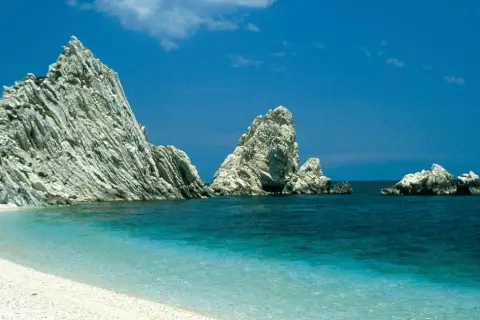 Spiaggia bianca e mare cristallino, rocce imponenti emergono dall'acqua turchese. Un angolo di paradiso nelle Marche, mare bello da cartolina.