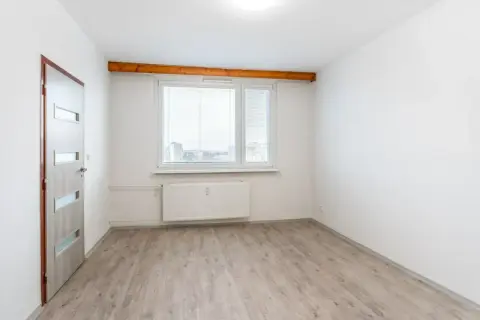 Puste pomieszczenie z drzwiami i oknem, gotowe do zamieszkania. To może być pierwsze mieszkanie komunalne.