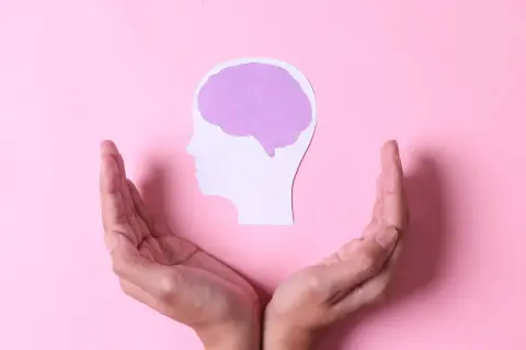 Dłonie otaczają profil głowy z mózgiem, symbolizując brak emocji po traumie i potrzebę wsparcia.