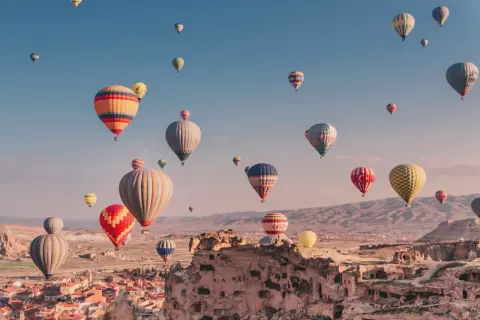 Många färgglada luftballonger svävar över Cappadocias unika landskap i Turkiet. En magisk luftballong turkiet-upplevelse.
