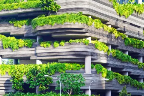 Edificio moderno con balcones cubiertos de vegetación exuberante, un ejemplo vivo de que es la sustentabilidad en la arquitectura.