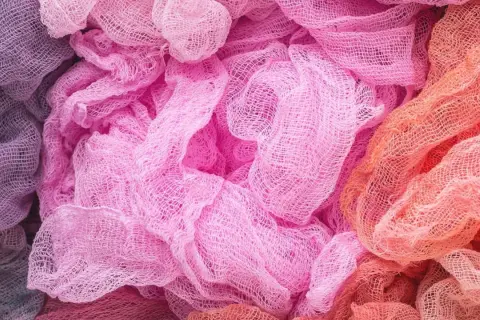 Tessuti morbidi e drappeggiati in tonalità pastello, dal lilla al rosa acceso fino all'arancio. Un'ispirazione per chi vuole imparare come decolorare un tessuto e creare sfumature uniche.