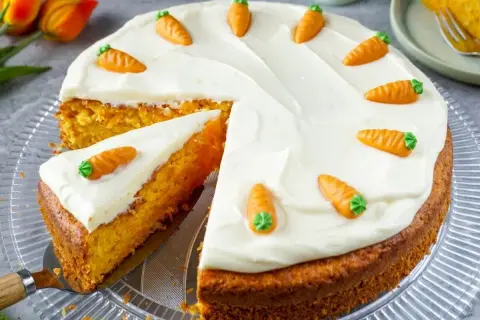 Ein saftiger Karottenkuchen mit cremigem Frosting, dekoriert mit kleinen Marzipan-Karotten. Perfekt für ein leckeres karottenkuchen rezept.