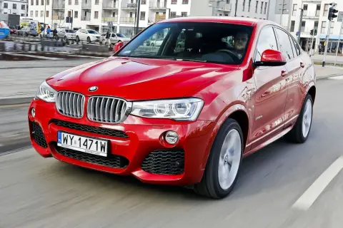 Czerwone BMW X4 2025 pędzi ulicą, błyszcząc w słońcu. Kierowca w środku, gotowy na przygodę.