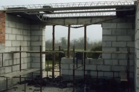 Budowa domu w toku. Widać betonowe pustaki, rusztowania i elementy stropu żelbetowego.