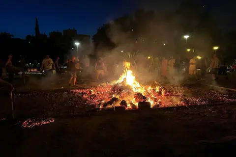 Gente reunida alrededor de una gran hoguera en Zaragoza, celebrando las hogueras de San Juan.