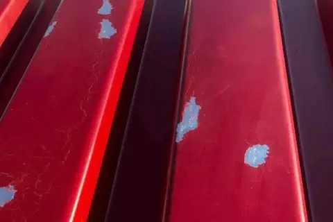 Detalles de la chapa galvanizada roja con pintura descascarada, mostrando el proceso de pintar chapa galvanizada.