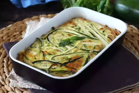 En gyllene frittata i ugn med tunna skivor zucchini och färska örter. En härlig rätt som doftar sommar.
