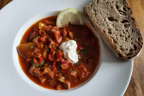 Herzhafte Soljanka, ein DDR-Rezept, mit saurer Sahne, Zitrone und Brot.