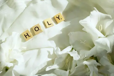 Litania do Ducha Świętego, pełna mocy, układa się w słowo "HOLY" wśród białych kwiatów i zwiewnej tkaniny.