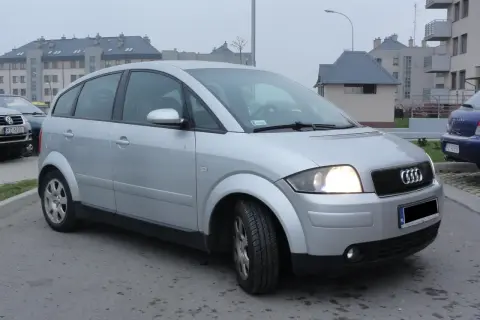 Srebrny Audi A2 1.4 benzyna zaparkowany przed blokami.