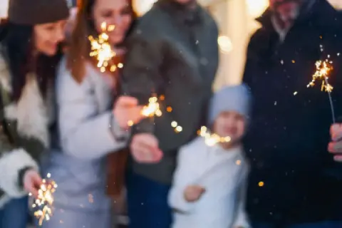 Rodzina z dziećmi świętuje Sylwestra, trzymając zimne ognie. Idealne miejsce, gdzie na sylwestra z dziećmi, by stworzyć magiczne wspomnienia.