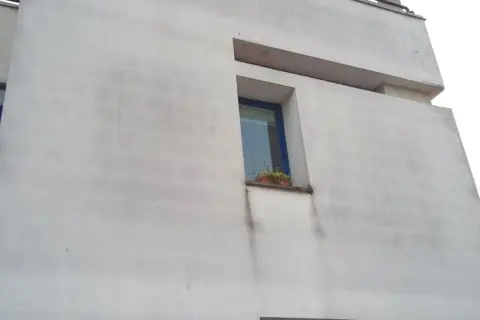 Facciata di un edificio con cappotto termico che mostra segni di muffa e macchie scure sotto la finestra.