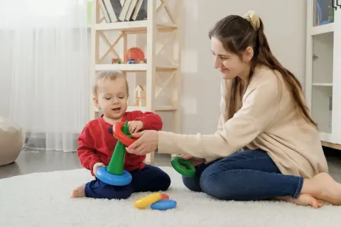 Mama i dziecko bawią się kółkami, rozwijając zdolności motoryczne. Radość i nauka w jednym.