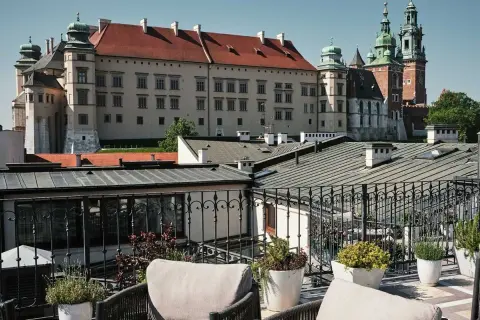 Widok z tarasu krakowskiego hotelu spa na Wawel. Wygodne fotele i rośliny tworzą relaksującą atmosferę.
