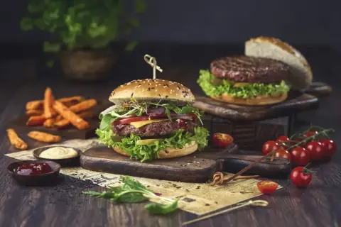 Pyszny hamburger, którego skąd pochodzi, z soczystą wołowiną, warzywami i serem, podany z frytkami i sosami.