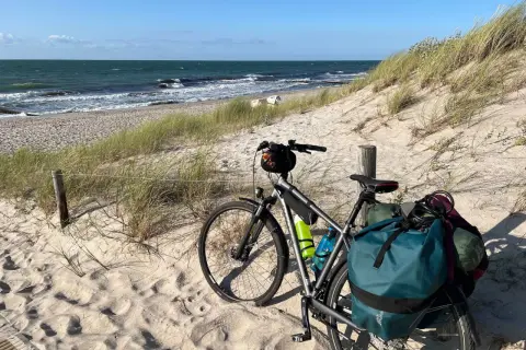 Rower z sakwami na piaszczystej plaży, gotowy na przygodę. Trasa rowerowa nad morzem czeka!