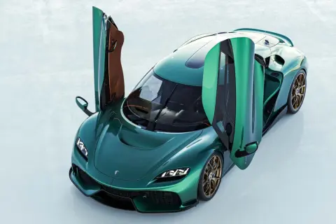 Zielony Koenigsegg Gemera z otwartymi drzwiami, prezentujący swoje luksusowe wnętrze i sportowy design.