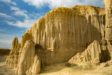 Formaciones rocosas erosionadas que recuerdan a la **Capadocia aragonesa** bajo un cielo azul con nubes.