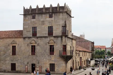 Plaza de Cambados que ver: torre medieval de piedra, casas históricas y gente paseando.