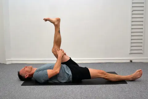 Man utför en leg curl svenska på en yogamatta, sträcker ut ena benet och böjer det andra.