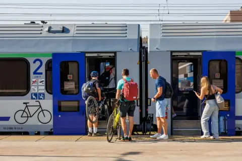 Ludzie z rowerami wsiadają do pociągu, szukając tanich biletów Intercity na wakacyjną podróż.