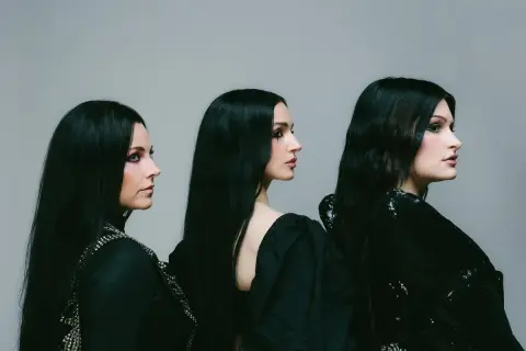 Drei Frauen mit langen schwarzen Haaren und dunklem Make-up, die wie eine Metal-Band posieren.