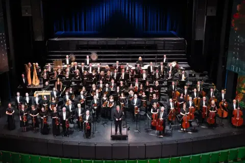 Wielka orkiestra symfoniczna na scenie, muzycy w strojach galowych, dyrygent. To właśnie opera co to za widowisko!