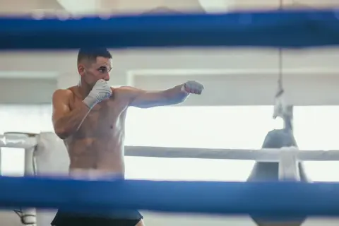 A boxer throws punches in a ring, practicing his moves. This is how shadow boxing, a training technique, likely began.