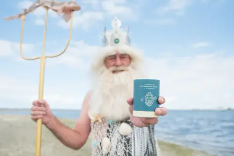 Neptunus, god van de zee, toont trots een potje Zeeuwse zoute met een vis aan zijn drietand.