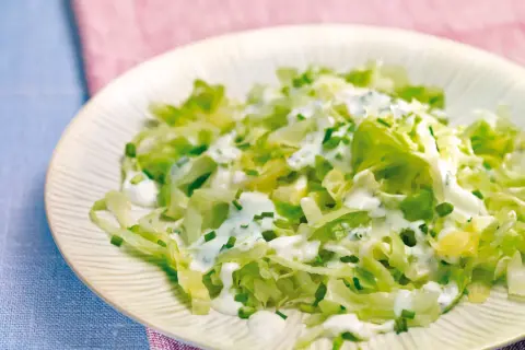 Frischer Spitzkohlsalat mit cremigem Dressing und Schnittlauch auf einem Teller.