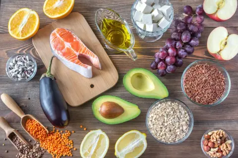 Assortiment d'aliments anti cholestérol : saumon, avocat, noix, lentilles, riz rouge, aubergine, agrumes, huile d'olive.
