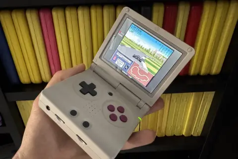 Gra wyścigowa na ekranie konsoli Game Boy Color, trzymanej w dłoni.
