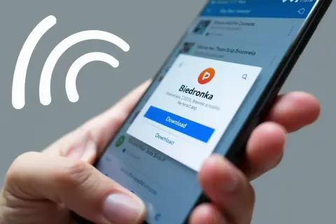 Dłoń trzyma smartfon, na ekranie którego wyświetla się okno pobierania aplikacji Biedronki.