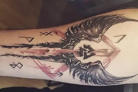 Tatuaż walka z samym sobą: symbolika run i skrzydła na przedramieniu.