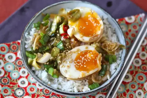 Skål med ris, halverade mayak gyeran-ägg, salladslök och sesamfrön.