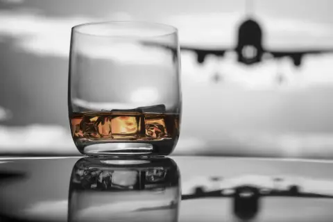 Szklanka whisky z lodem na tle samolotu. Czy można przewozić alkohol w samolocie Ryanair?