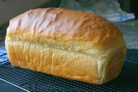 Pan de molde dorado y esponjoso enfriándose en una rejilla, perfecto para tus próximas recetas con pan de molde.