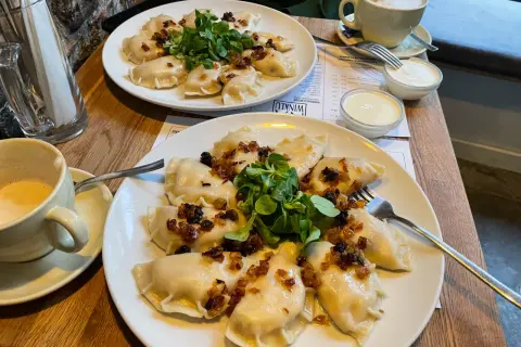 Pyszne pierogi z cebulką i zielenią to świetny pomysł, co zjeść w Poznaniu. Do tego kawa i śmietana.