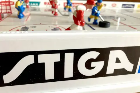 Stig Hjelmquist spelar hockey på STIGA-bordet. Röda och blå spelare kämpar om pucken på isen.