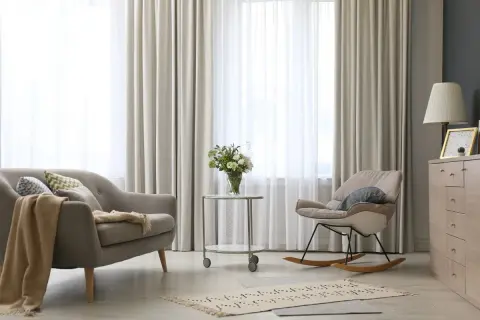 Elegantes tipos de cortinas para ventanas, con un sofá y mecedora en un salón moderno.