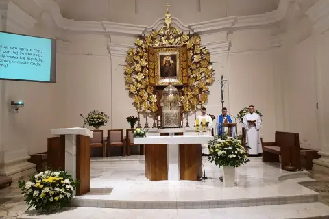 Msza w kościele w Dąbrówce Kościelnej. Trzech duchownych przy ołtarzu, ozdobionym złotym antepedium i obrazem Matki Boskiej.