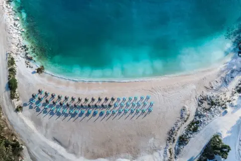 Rajska plaża na Thassos z turkusową wodą i rzędami leżaków. Idealne miejsce na relaks i podziwianie pięknych widoków.