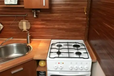 Kuchenny blat z drewnianym wykończeniem, zlewozmywak i kuchenka gazowa. Idealne miejsce do łączenia blatu kuchennego z innymi elementami.