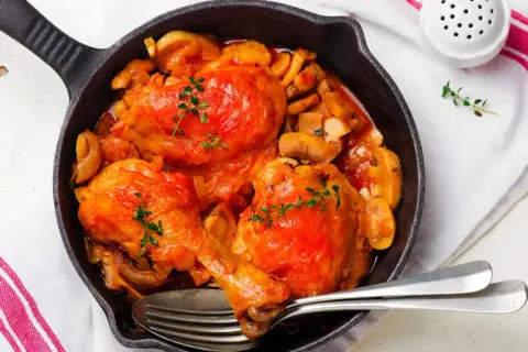 Poulet Marengo mijoté dans une poêle en fonte avec des champignons et garni de thym.