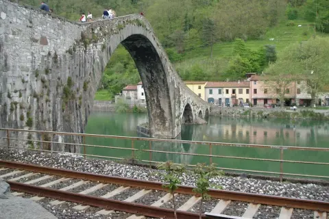 Ponte del Diavolo a Borgo a Mozzano, con case colorate e un fiume verde.