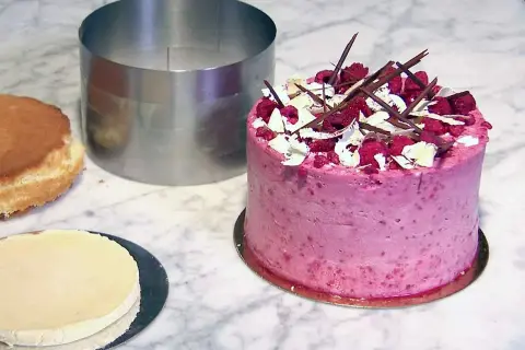 En vacker hallontårta med chokladdekorationer och grädde. Perfekt tårta inspo för nästa bakprojekt!